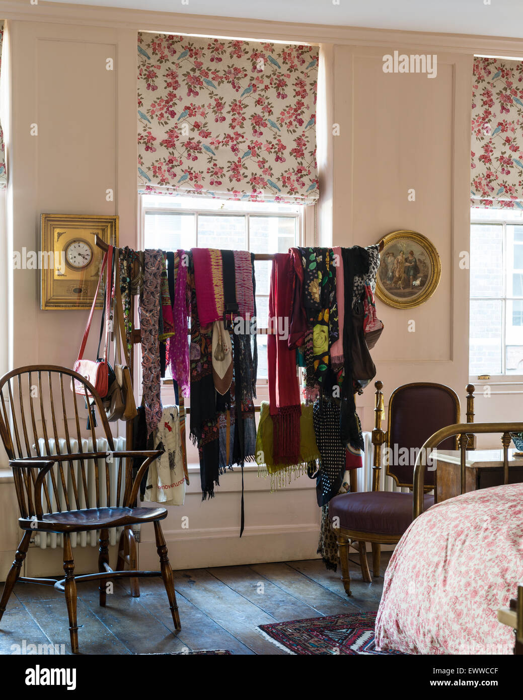 Sortierte Schals hingen an einen chinesischen Kleiderständer in Schlafzimmer mit floral gemusterte Vorhänge und Windsor Stuhl Stockfoto