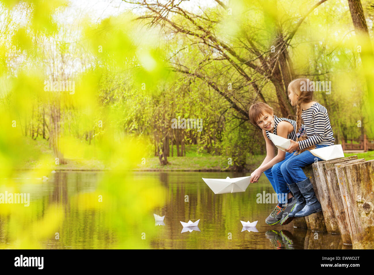 Jungen und Mädchen spielen mit Papier Boote auf dem Flusswasser Stockfoto