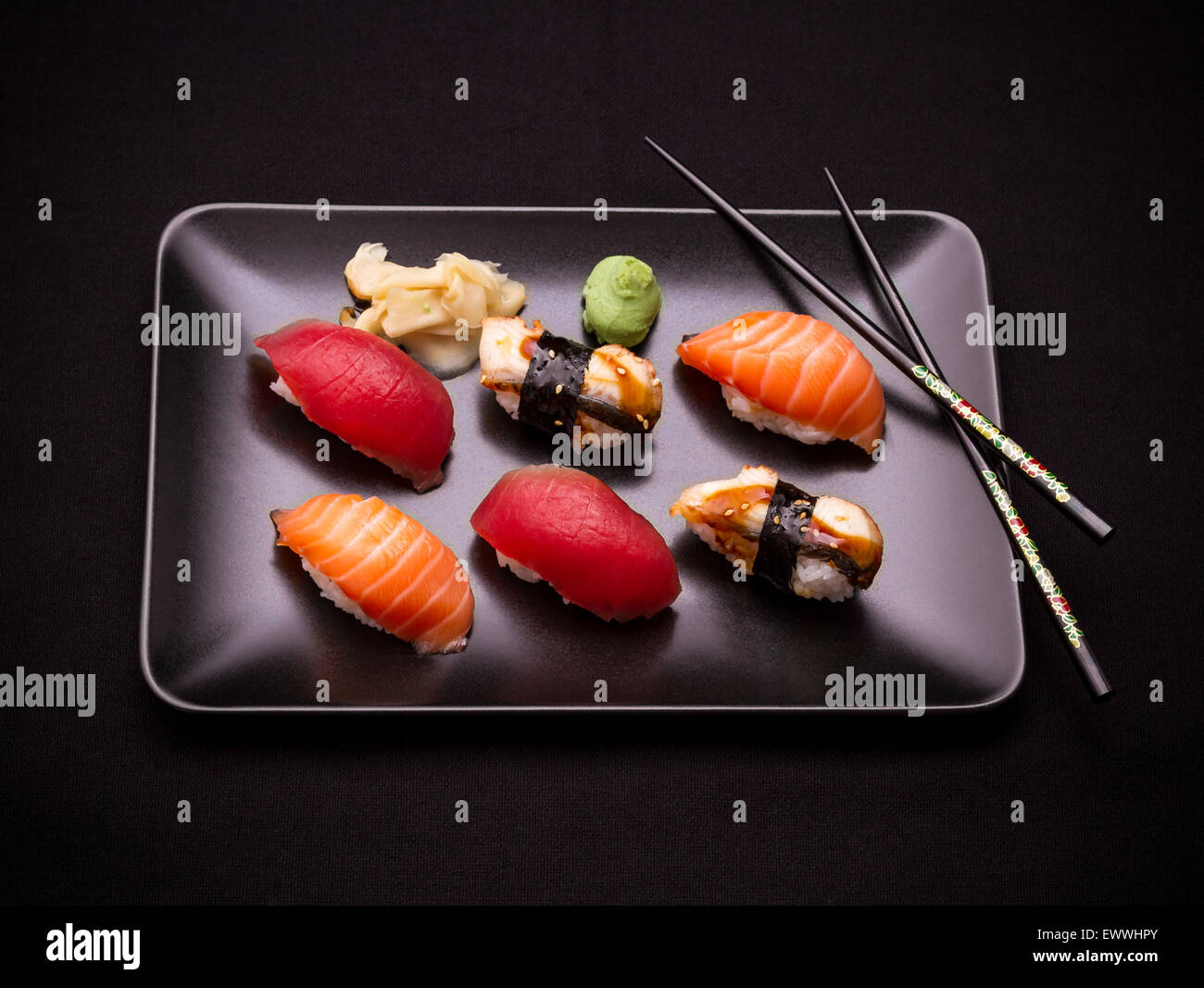 Aal, Lachs und Thunfisch Sushi mit Stäbchen, dunkler Hintergrund Stockfoto
