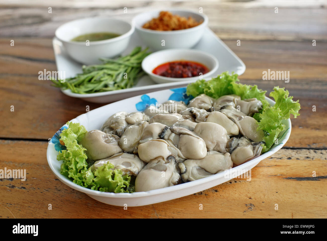 frische Austern mit Beilagen auf Schreibtisch aus Holz Stockfoto
