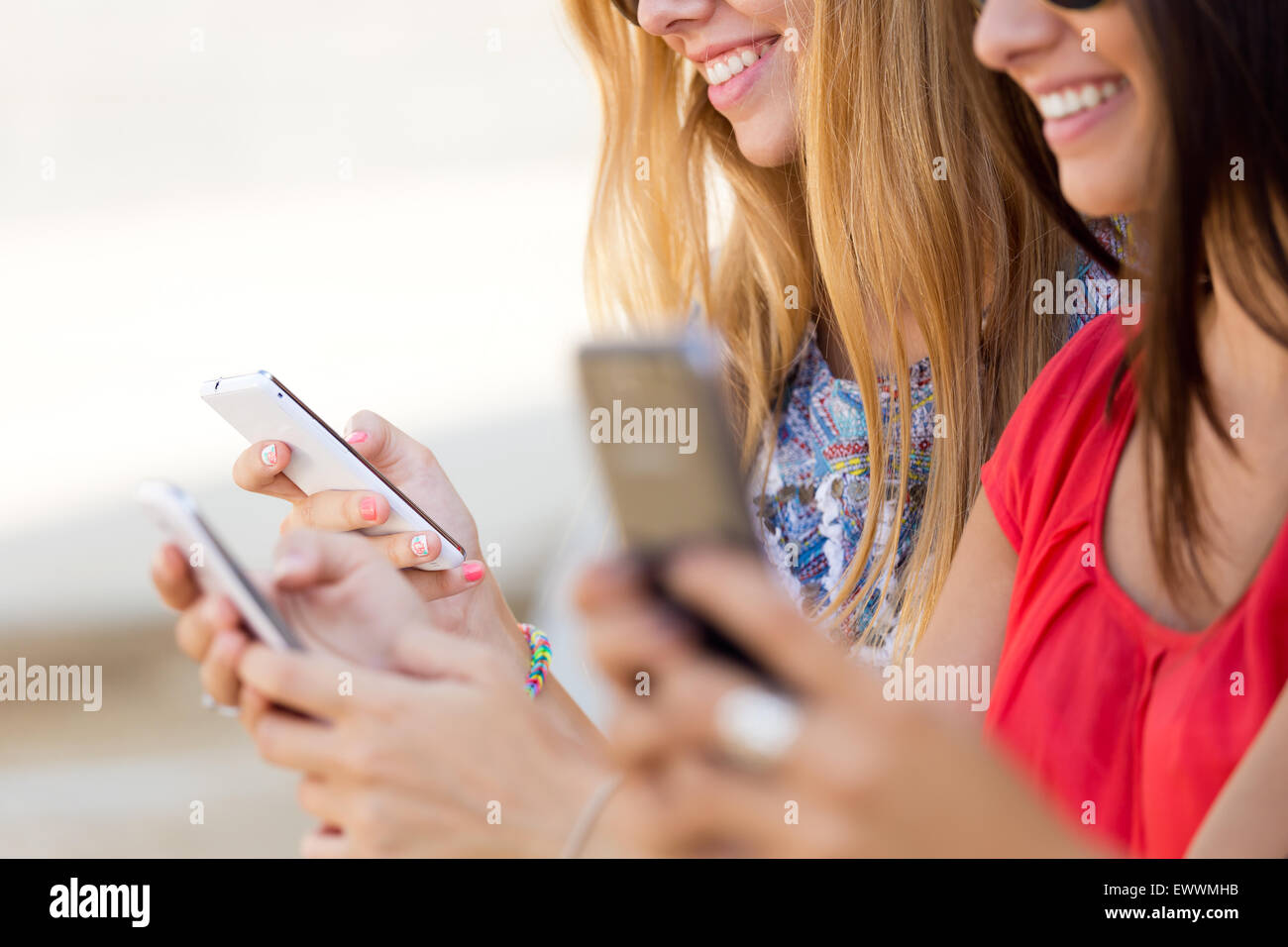 Porträt von drei Mädchen im Chat mit ihren Smartphones auf dem campus Stockfoto