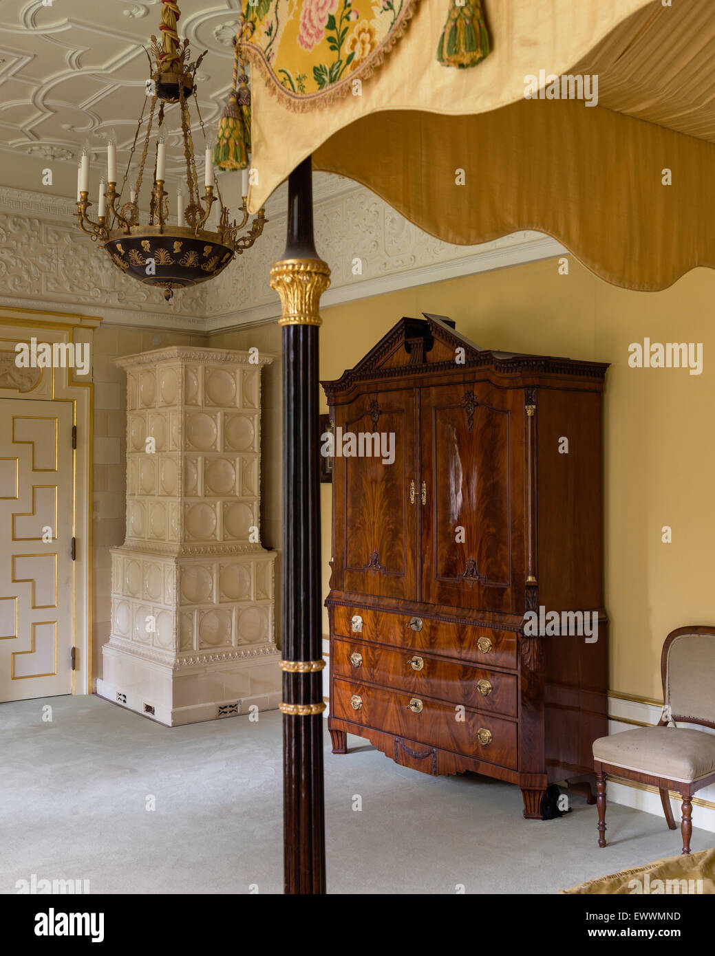 Antiker Schrank im Schlafzimmer mit Kachelofen, Stuckdecke und Himmelbett Stockfoto