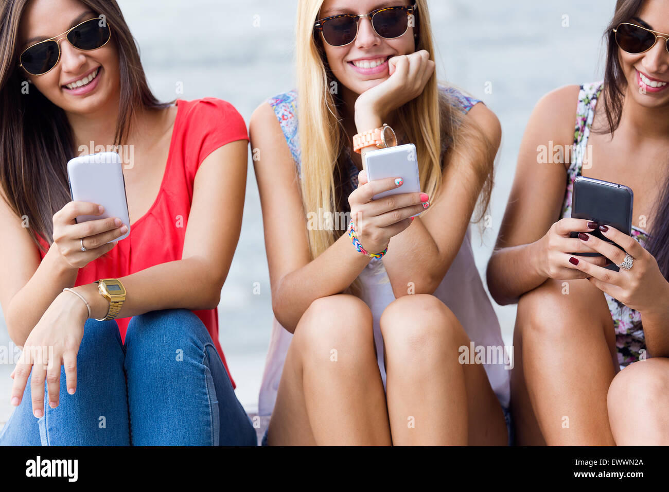 Porträt von drei Mädchen im Chat mit ihren Smartphones auf dem campus Stockfoto