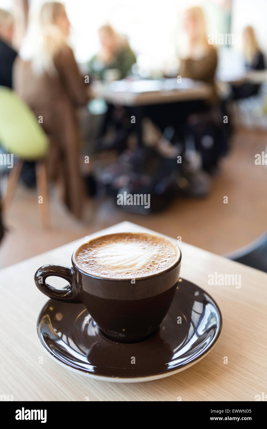 Aus Fokus Schuss von einem Café bei einer Tasse Cappuccino im Vordergrund, Stockfoto