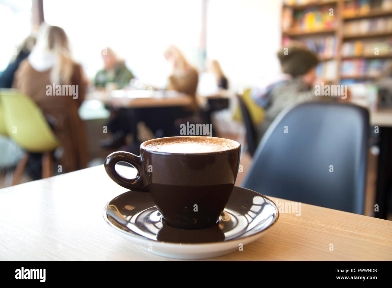 Gedreht in einem Café, Tasse Cappuccino in den Vordergrund und verschwommen Gäste an Tischen im Hintergrund unscharf Stockfoto