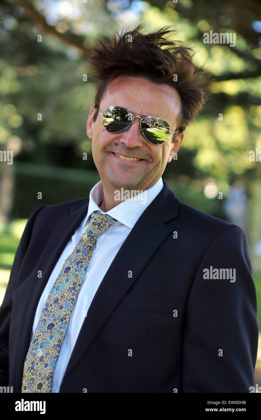 Intelligente Mann mittleren Alters im Business-Anzug und Sonnenbrille mit Haaren im Wind wehen Stockfoto