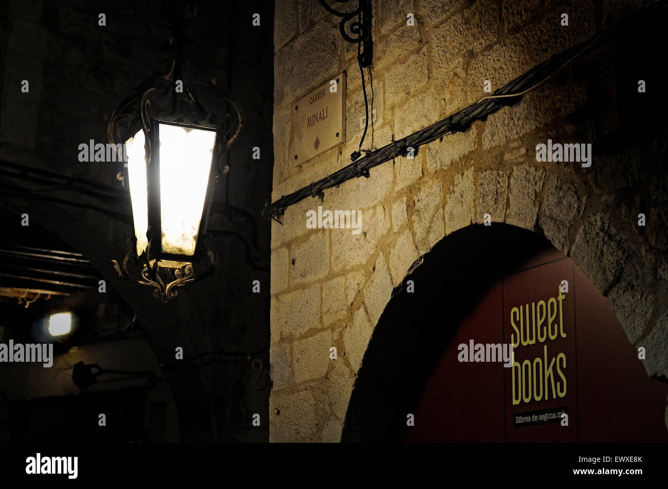 Beleuchtete Laterne in der Nacht vor einem gewölbten Bibliothek "Tür in der Altstadt von Girona. Katalonien. Spanien. Stockfoto