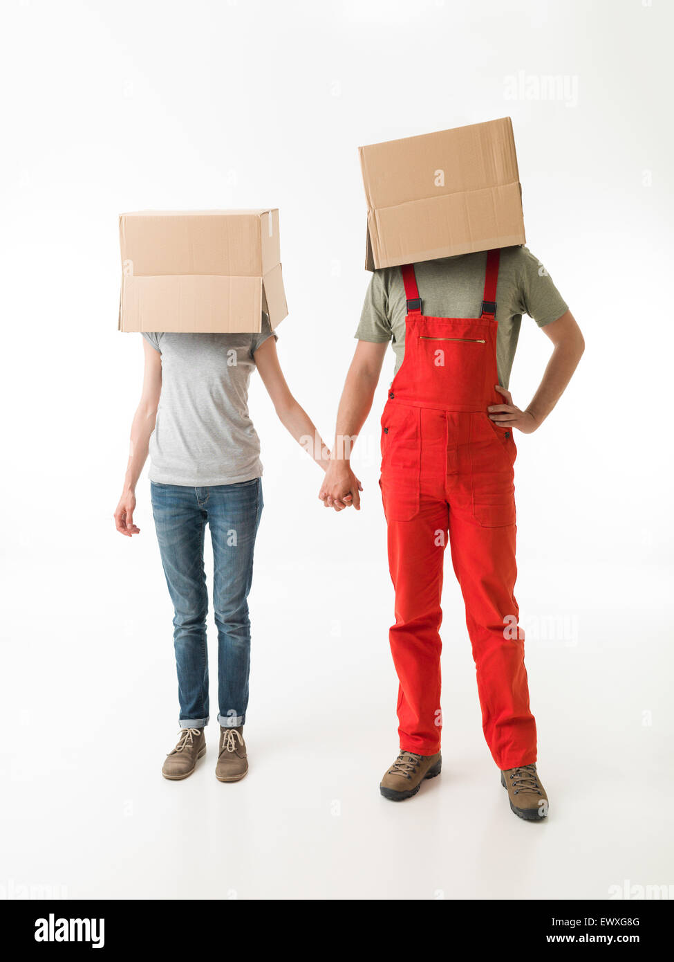 junges Paar mit Kartons auf dem Kopf, Hand in Hand, auf weißem Hintergrund Stockfoto