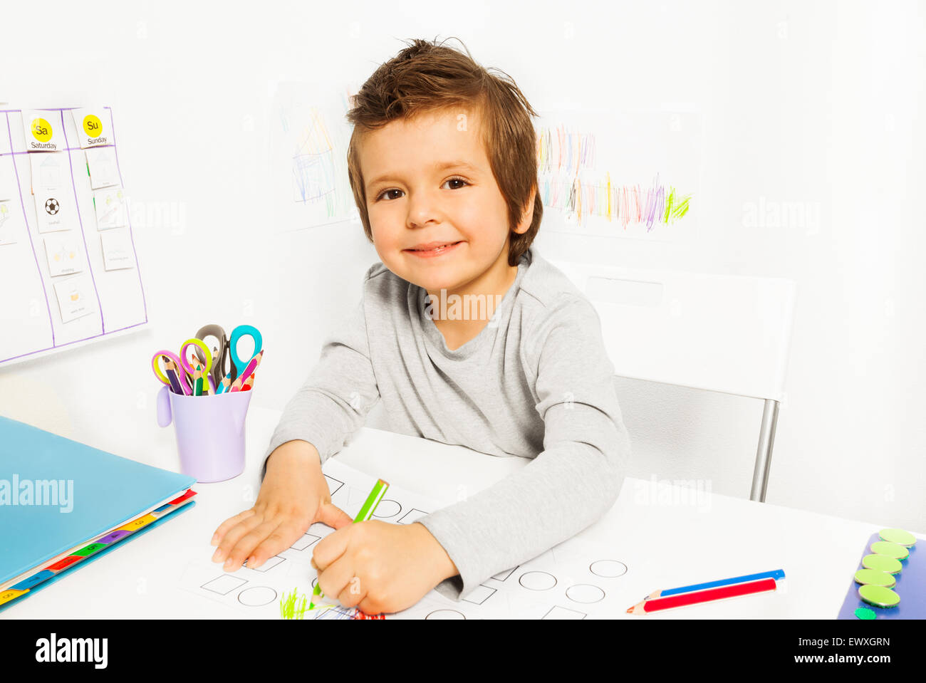Positive kleiner Junge zieht mit Bleistift in ABA Stockfoto