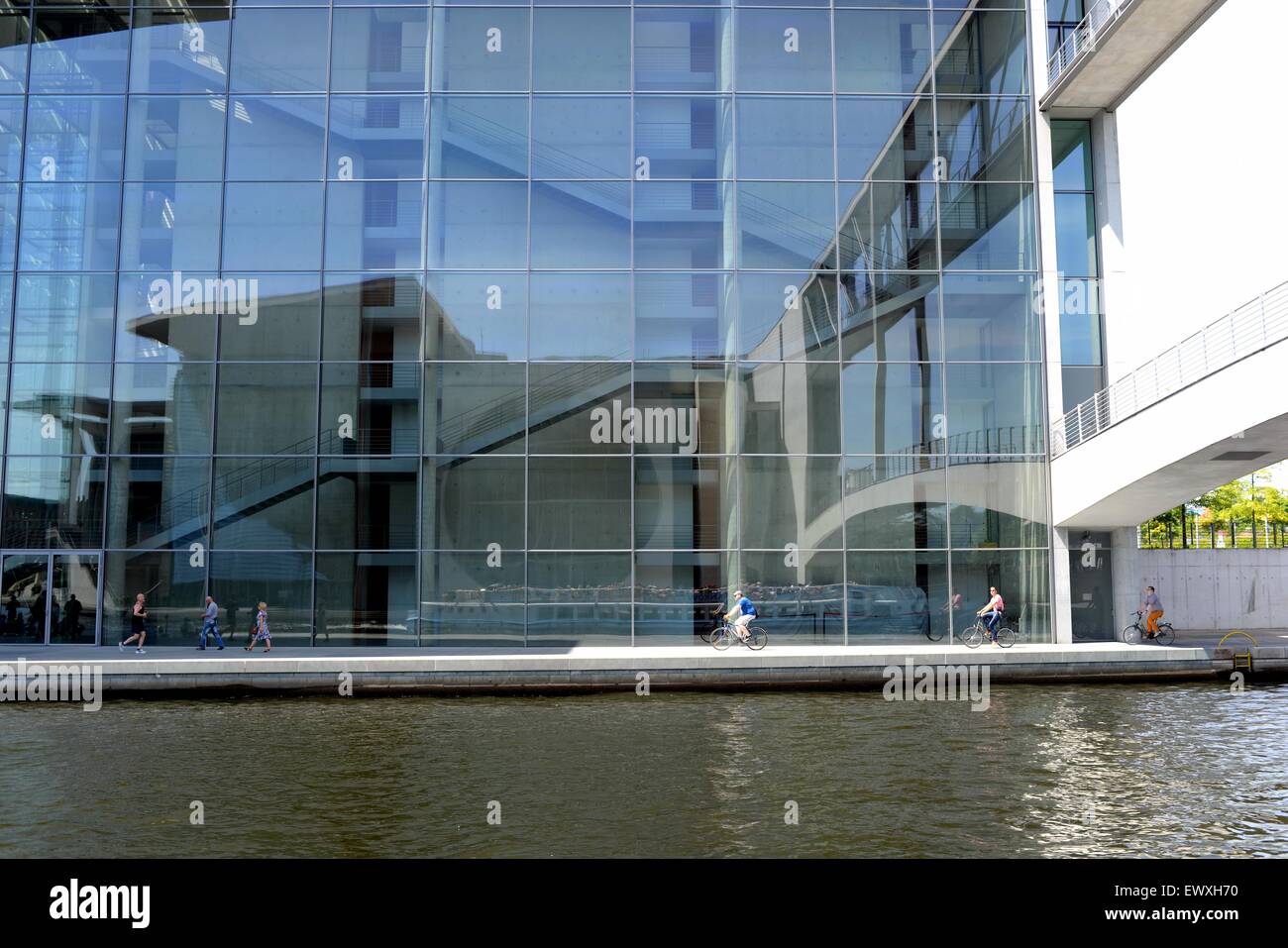 Moderne Regierungsgebäude mit Glasfassade in Berlin, Deutschland, mit Reflektion, Radfahrer und Fluss. Stockfoto