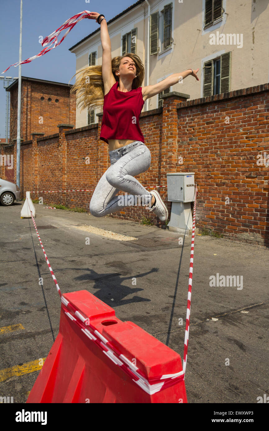 Junges blondes Mädchen genießt das Leben in einem städtischen Raum (ein Platz) in Chieri (Torino) an einem Sommertag tanzen Stockfoto