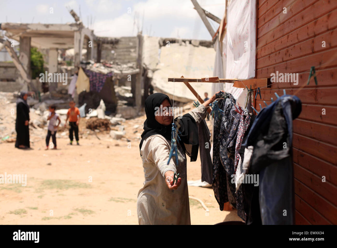 Khan Younis, Gazastreifen, Palästinensische Gebiete. 2. Juli 2015. Eine Palästinenserin sammelt Wäscherei in der Nähe der Ruinen von ihrem Haus, die Zeugen sagten durch israelischen Beschuss in einem 50-Tage-Krieg letzten Sommer in Khan Younis im südlichen Gazastreifen 2. Juli 2015 zerstört wurde. Robert Turner hat keine schnelle und einfache Antwort gefragt, um die schlimmsten Zeiten in seinen drei Jahren laufenden Hilfsmaßnahmen der Vereinten Nationen in Gaza Credit zu nennen: Ashraf Amra/APA Bilder/ZUMA Draht/Alamy Live News Stockfoto