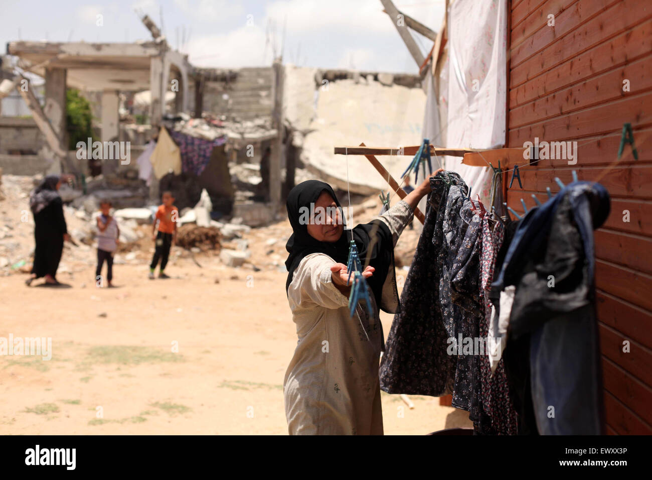 Khan Younis, Gazastreifen, Palästinensische Gebiete. 2. Juli 2015. Eine Palästinenserin sammelt Wäscherei in der Nähe der Ruinen von ihrem Haus, die Zeugen sagten durch israelischen Beschuss in einem 50-Tage-Krieg letzten Sommer in Khan Younis im südlichen Gazastreifen 2. Juli 2015 zerstört wurde. Robert Turner hat keine schnelle und einfache Antwort gefragt, um die schlimmsten Zeiten in seinen drei Jahren laufenden Hilfsmaßnahmen der Vereinten Nationen in Gaza Credit zu nennen: Ashraf Amra/APA Bilder/ZUMA Draht/Alamy Live News Stockfoto