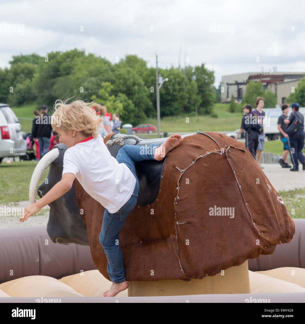 Kleiner Junge wird von einem mechanischen Bullen am Canada Day Feierlichkeiten in Cannington, Ontario ausgelöst. Stockfoto