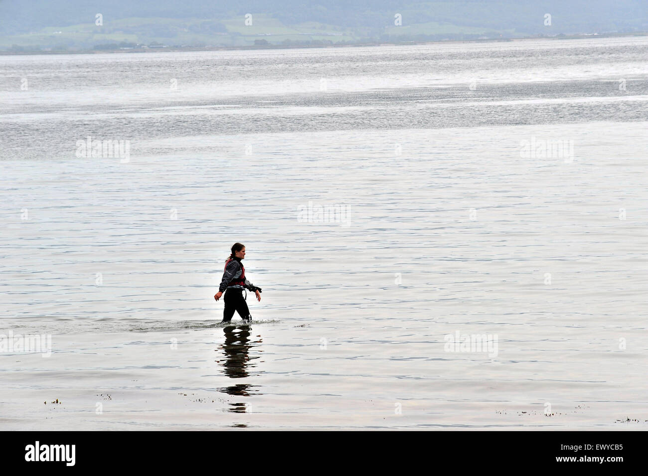 Junge Frau trägt Neoprenanzug zu Fuß durch Wasser bei Moville, County Donegal, Irland Stockfoto