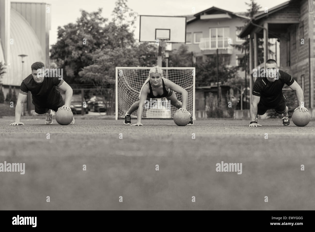 Eine Gruppe von jungen Leuten im Aerobic-Kurs durchführen Liegestütze auf Medizinball Übung im freien Stockfoto