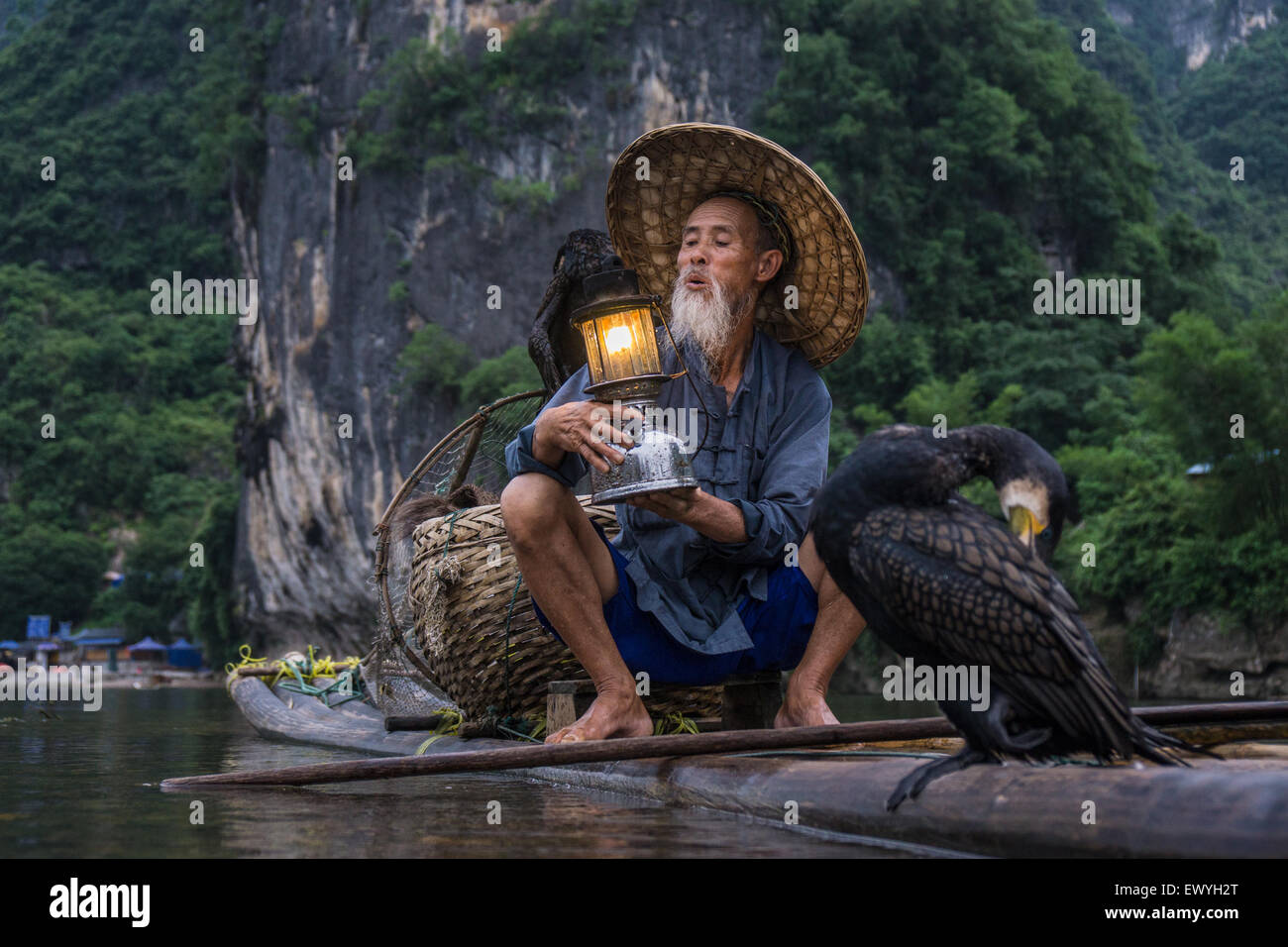 Kormoran Fischer auf einem Floß hält eine Laterne, Guilin, China Stockfoto