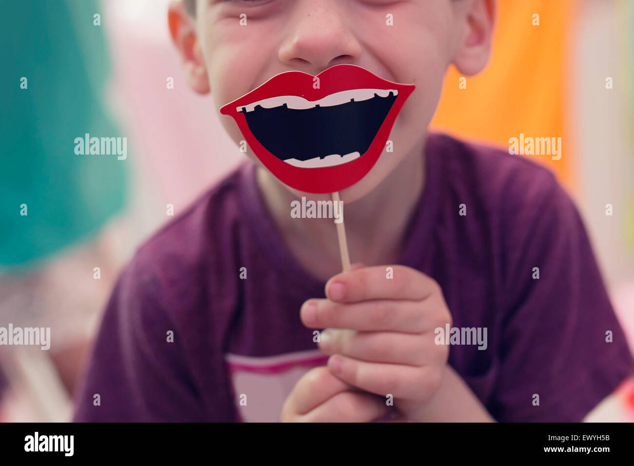 Junge hält eine Lächeln Prop auf einem stick Stockfoto