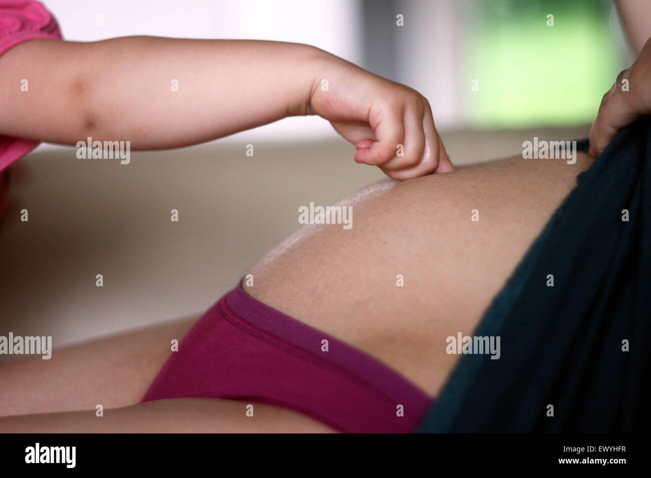Baby Hand berühren den Bauch der schwangeren Mutter Stockfoto