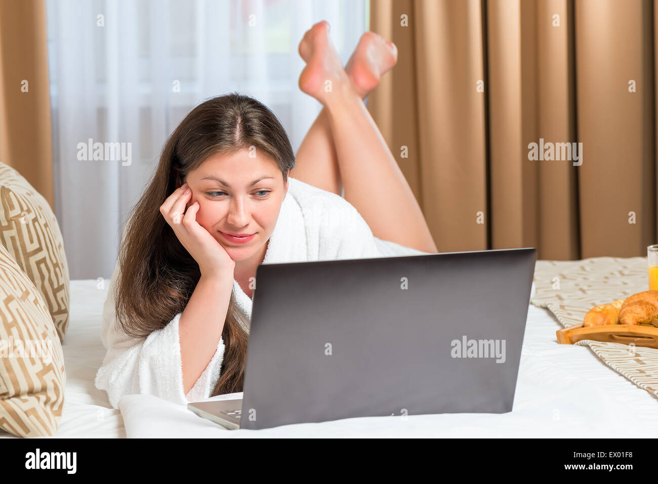 junge Frau mit einem Computer, auf dem Bett im hotel Stockfoto