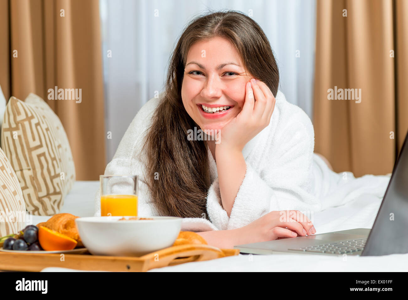 schöne und glückliche Mädchen auf dem Bett mit einem Tablett mit Essen Stockfoto
