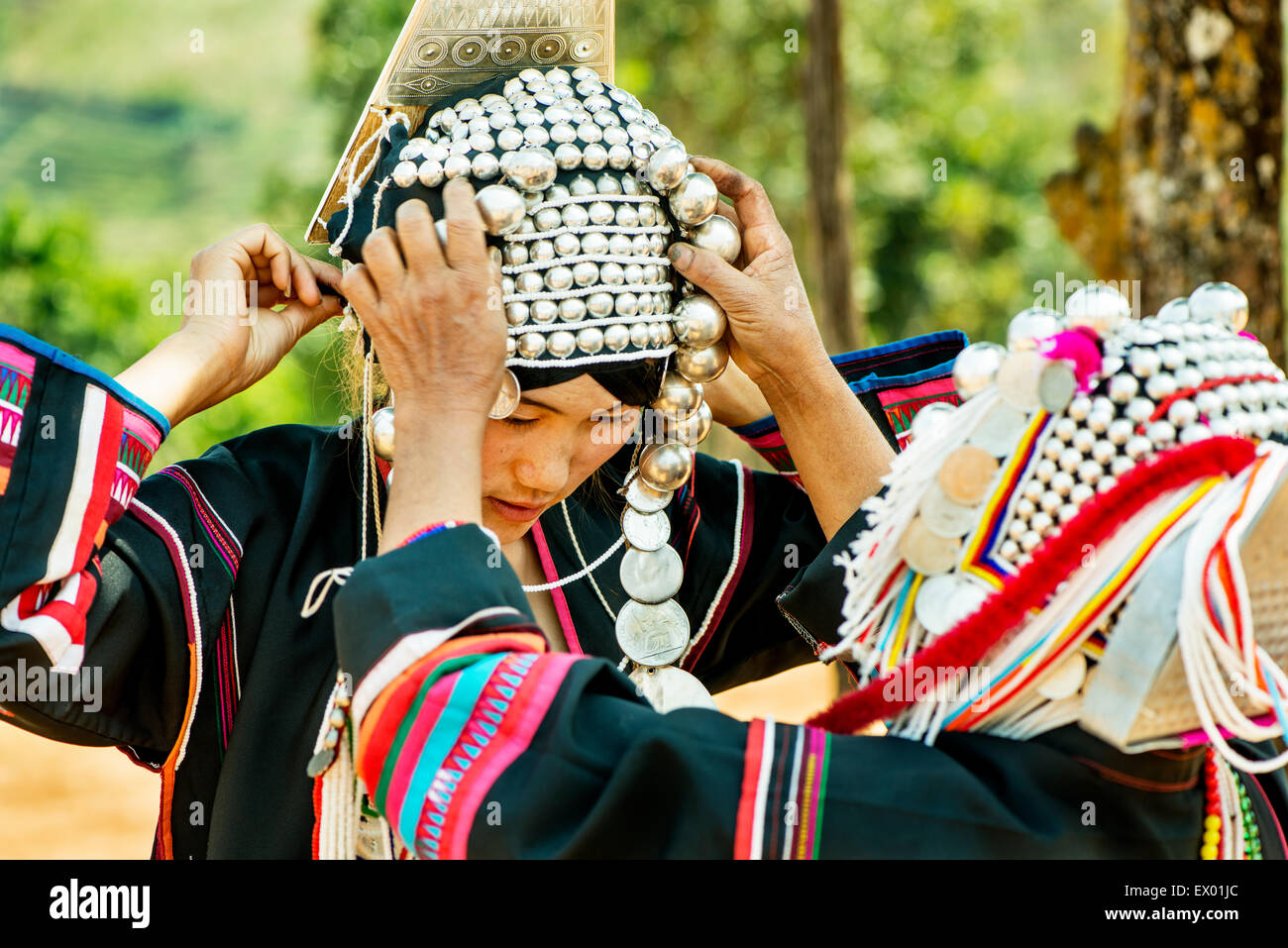 Akha jungen Frau geholfen, auf ihre traditionelle Kleidung in Mae Salong Dorf, Thailand, Asien. Stockfoto