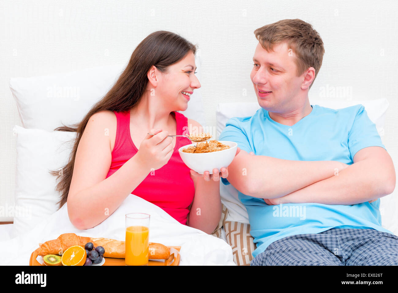 glückliches junges Paar zusammen im Bett frühstücken Stockfoto