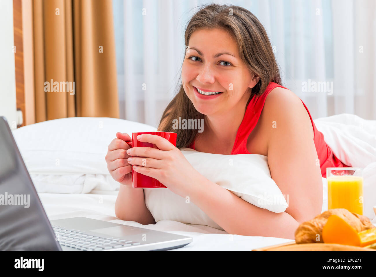 glückliche Frau mit einer Tasse heißen Kaffee am Morgen im Bett Stockfoto