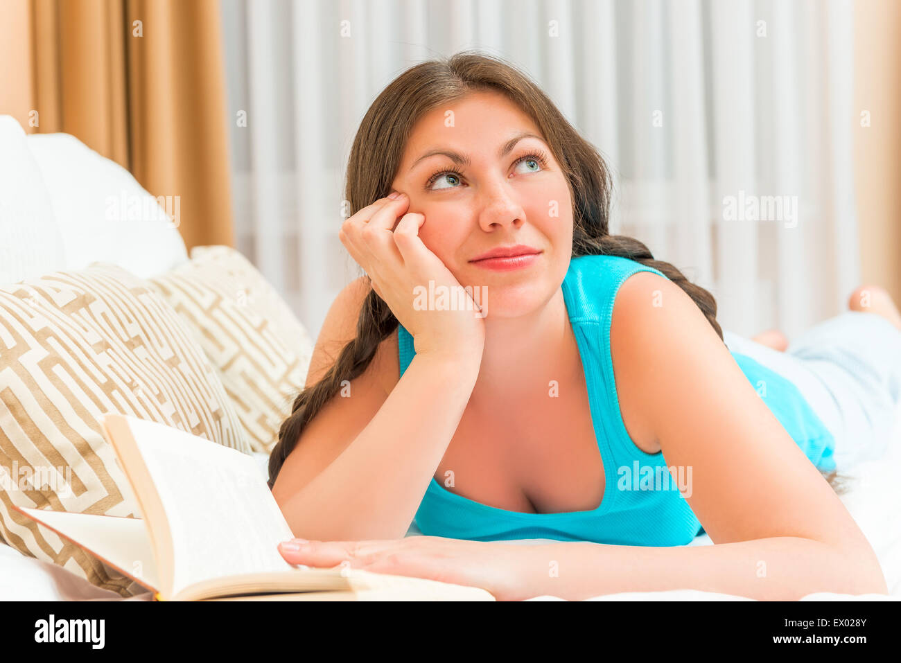 verträumte Mädchen mit einem Buch im Bett Stockfoto