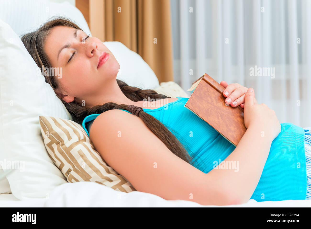 Student schlief auf dem Bett mit einem Buch in der hand Stockfoto
