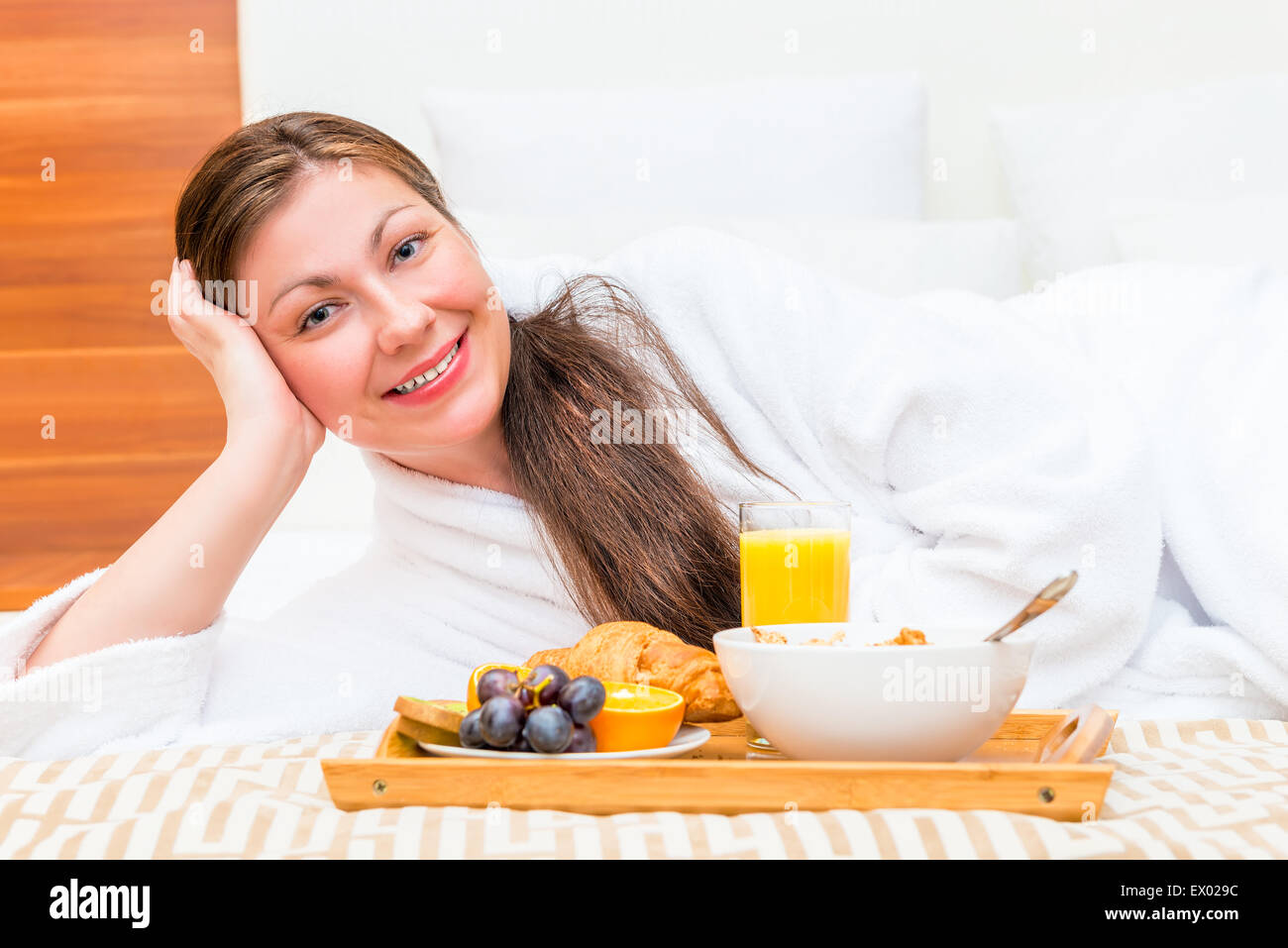 glücklich schöne Mädchen auf dem Bett mit einem Tablett mit Essen Stockfoto