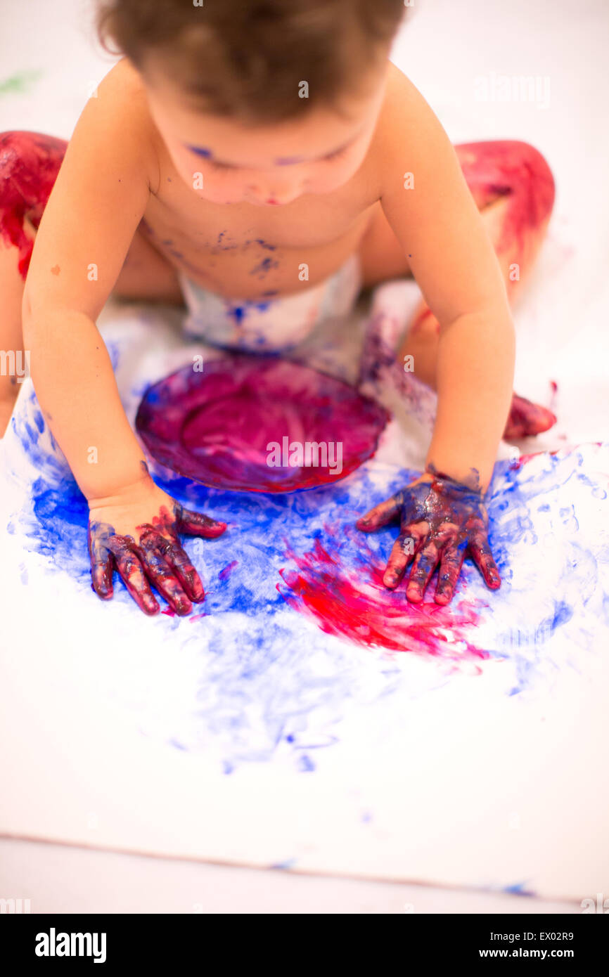 Babymädchen Dilettantismus mit Fingerfarben in weißen Küche Stockfoto
