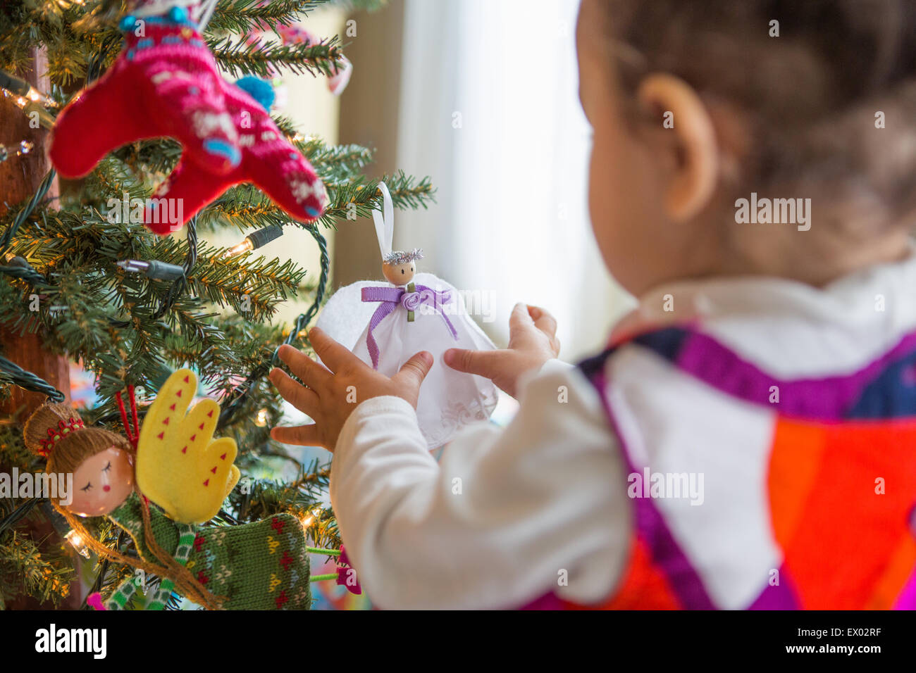 Kleines Mädchen betrachten Engel Ornament auf Weihnachtsbaum Stockfoto