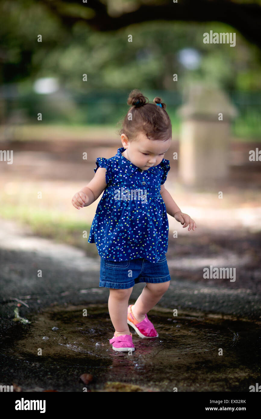 Kleine Mädchen gehen in Pfütze im park Stockfoto