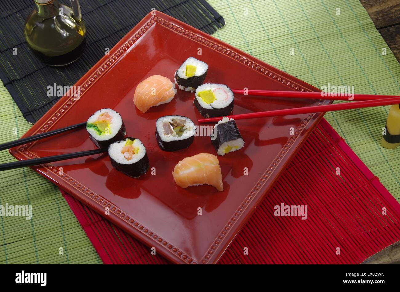 Portion Sushi und schwarze Hopsticks auf Teller Stockfoto