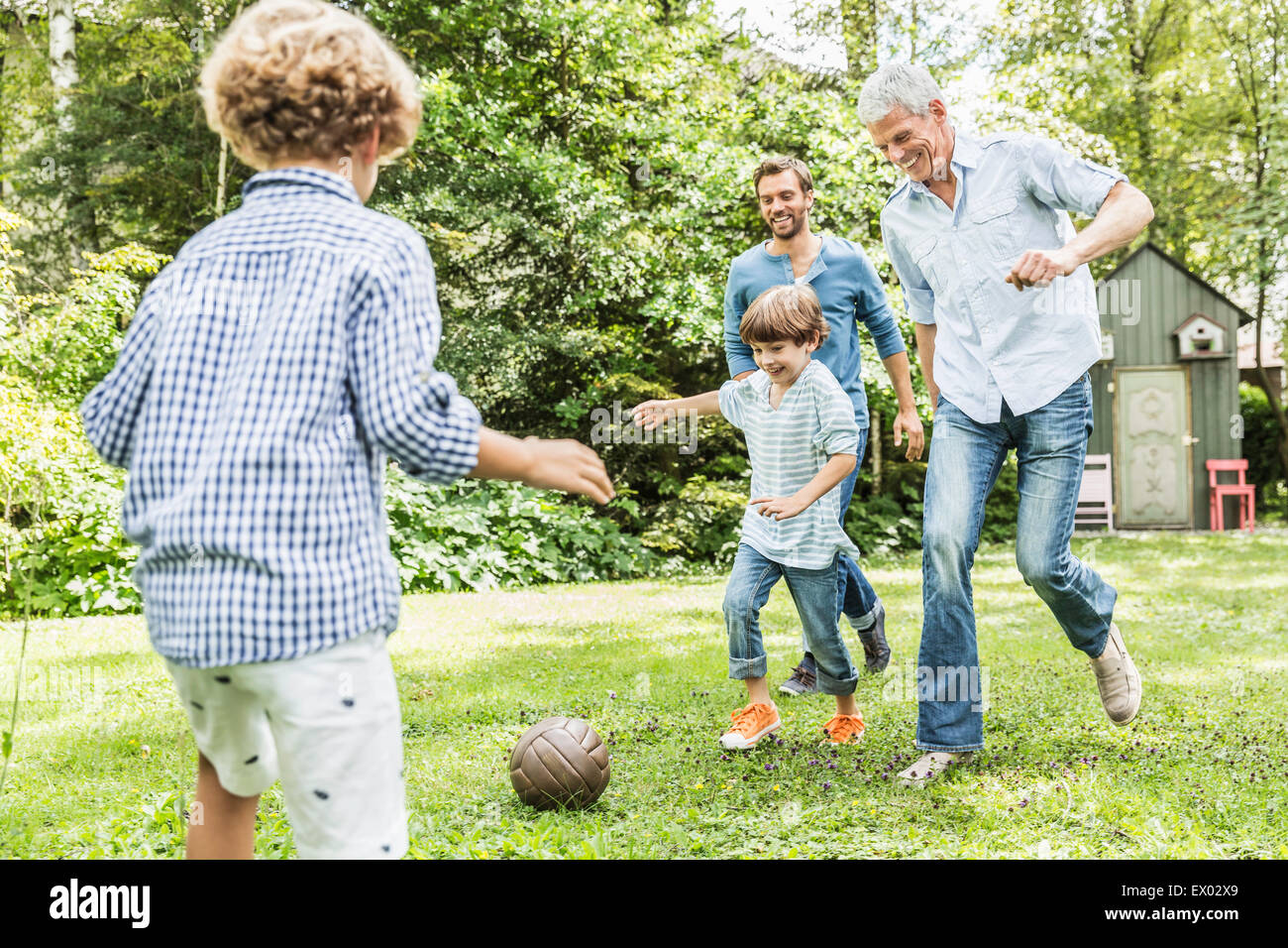 Mitte erwachsener Mann mit Vater und Söhnen Garten Fußball spielen Stockfoto