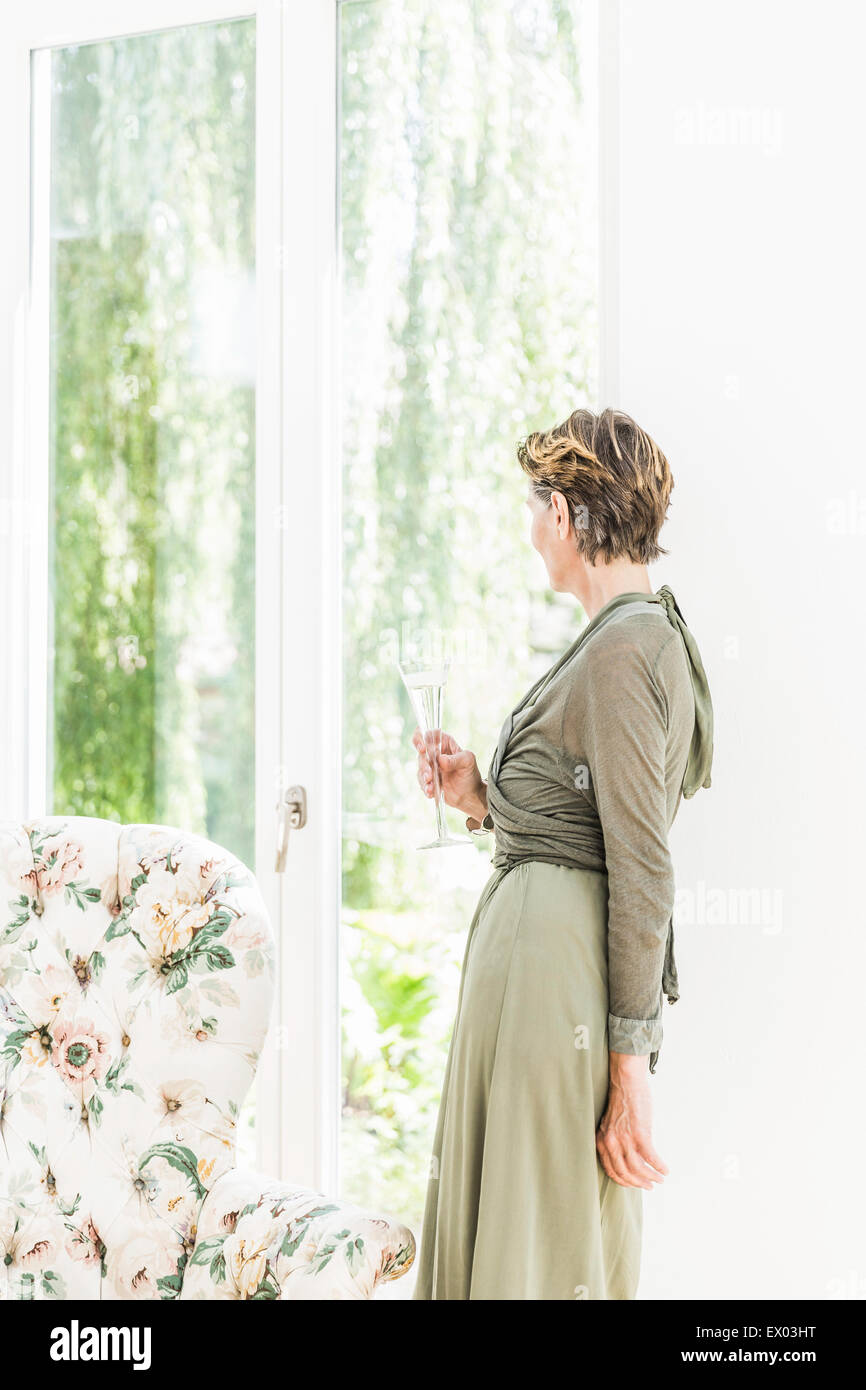 Porträt von senior Frau Blick aus Fenster im Wohnzimmer Stockfoto