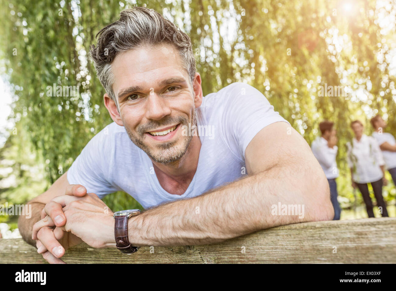 Porträt von Mitte erwachsener Mann stützte sich auf Zaun im Wald Stockfoto