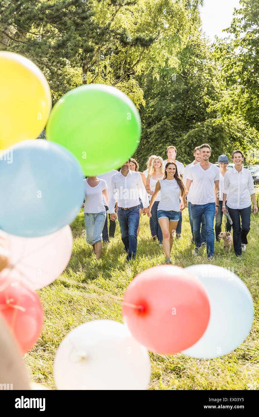 Gruppe von Menschen zu Fuß durch Wald, Party Luftballons im Vordergrund Stockfoto