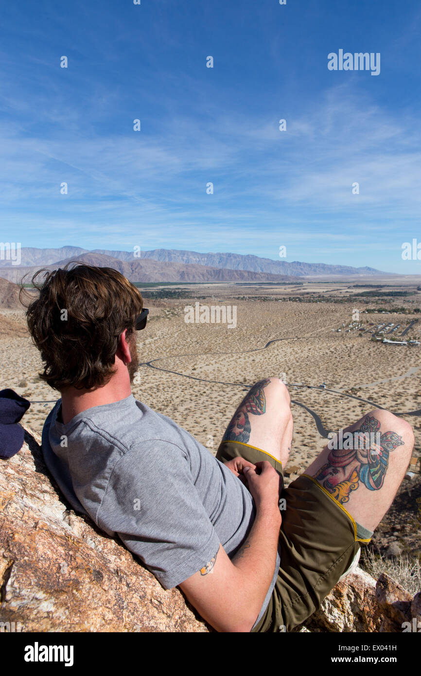 Junger Mann auf den Felsen mit Blick auf Landschaft, Anza-Borrego Desert State Park, Kalifornien, USA Stockfoto