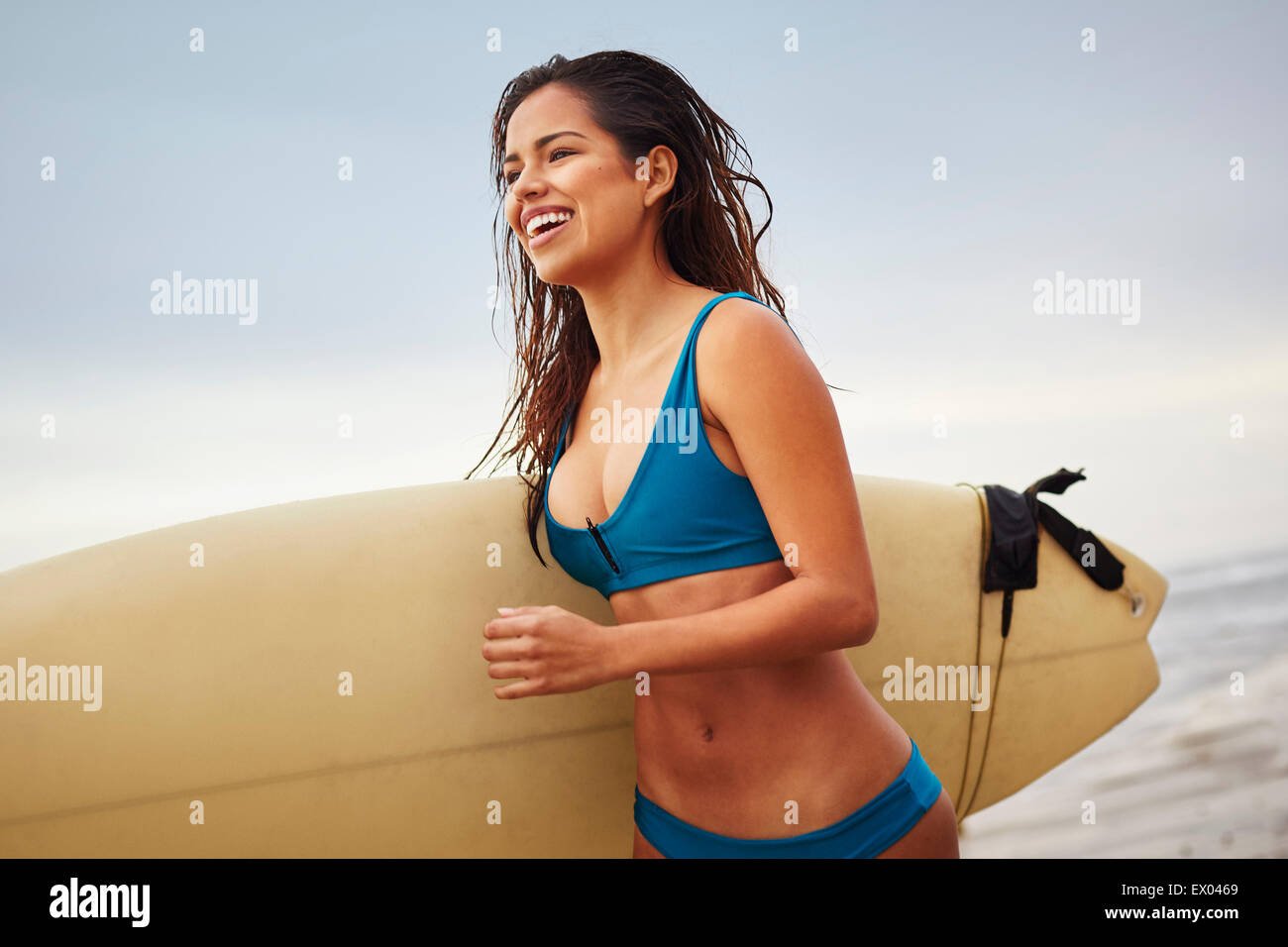 Junge Frau läuft am Strand tragen Surfbrett, San Diego, Kalifornien, USA Stockfoto