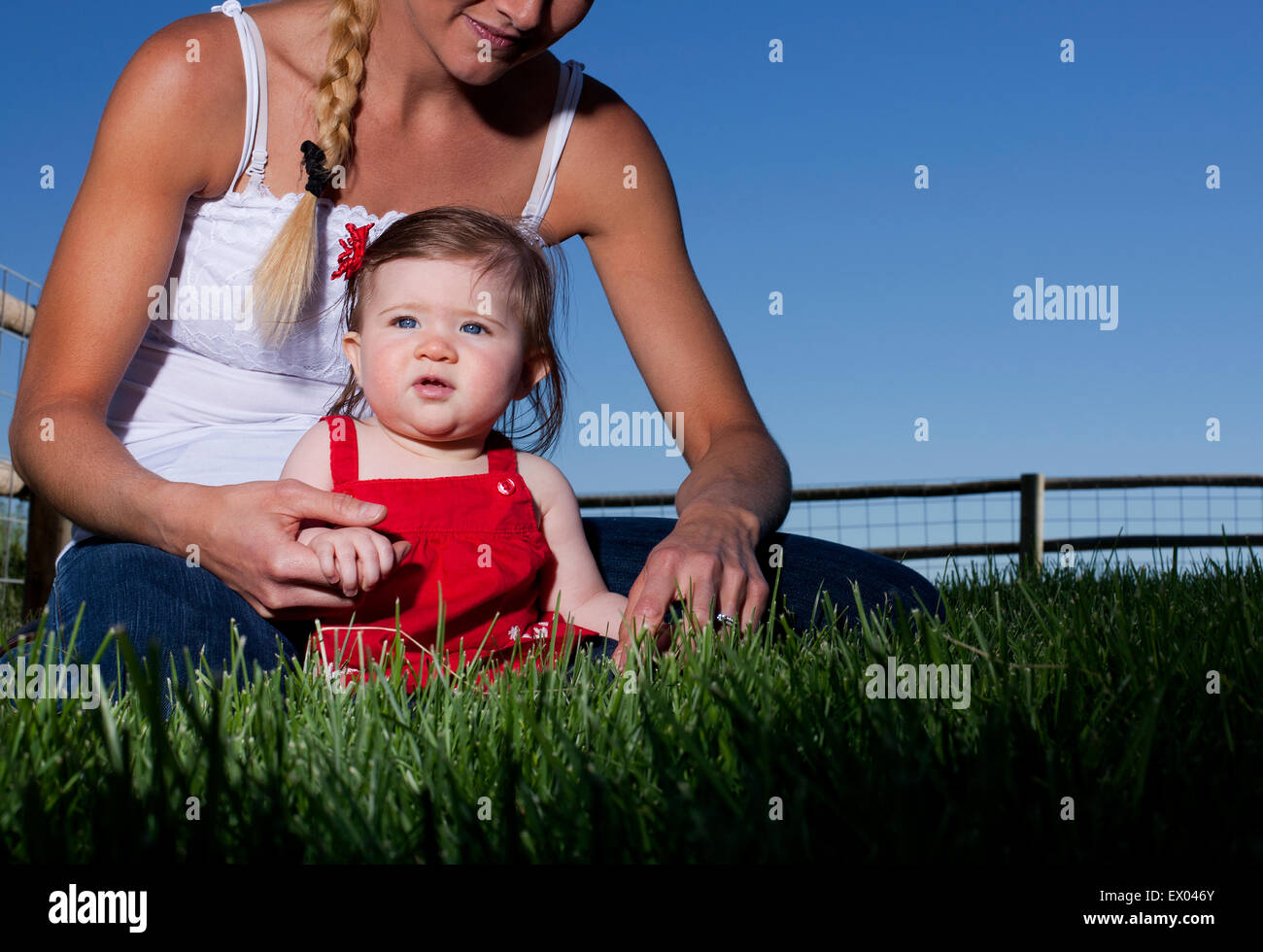 Porträt von Mitte Erwachsene Frau sitzen auf Rasen mit Kleinkind Tochter Stockfoto