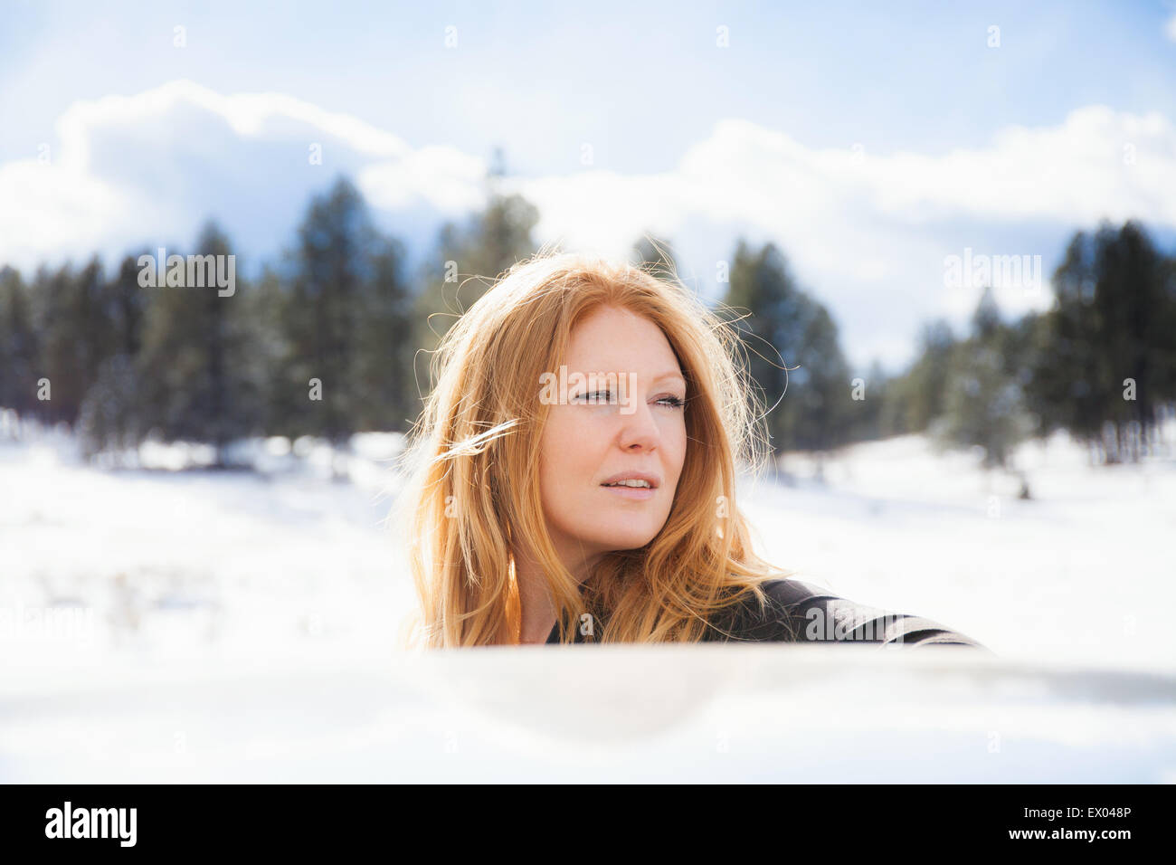 Porträt von Mitte Erwachsene Frau Blick auf Autodach in verschneite Landschaft Stockfoto