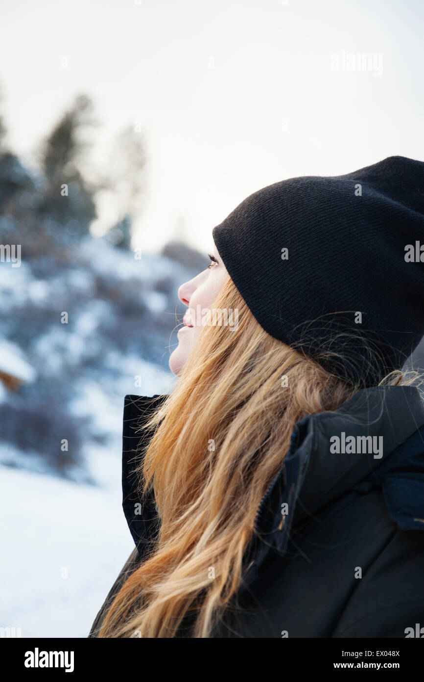 Mitte erwachsenen Frau in Strick Hut Blick auf verschneite Landschaft Stockfoto