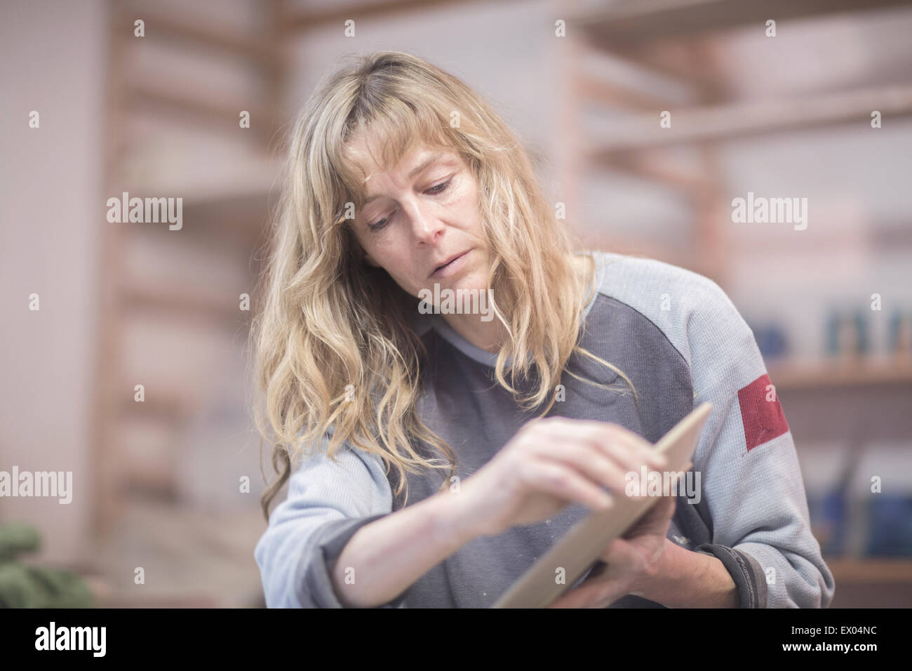 Weibliche Potter berühren Kante der Platte in Werkstatt Stockfoto