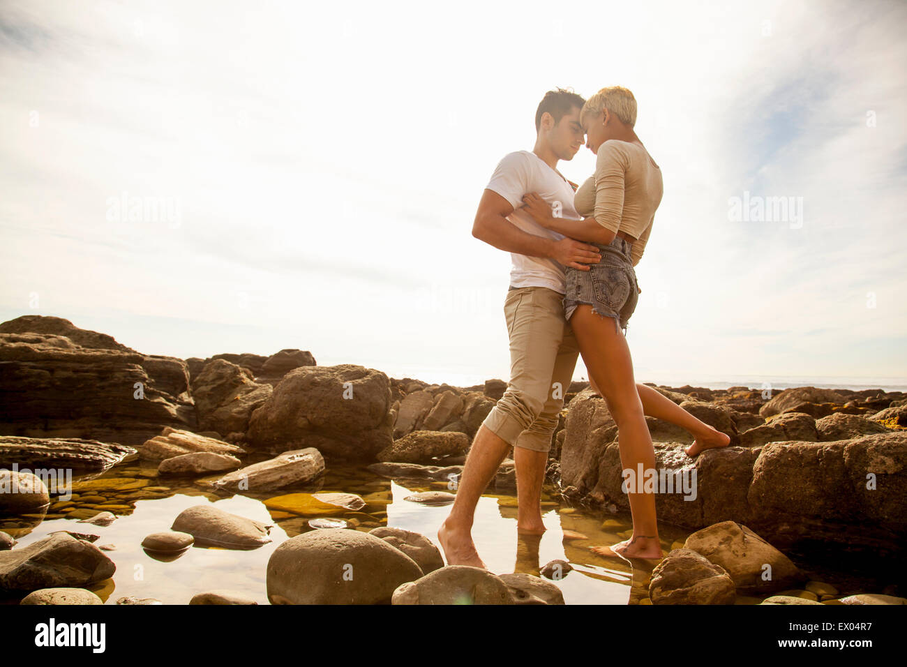 Junges Paar stehen zusammen, Angesicht zu Angesicht, in Felsen-Pool am Strand Stockfoto