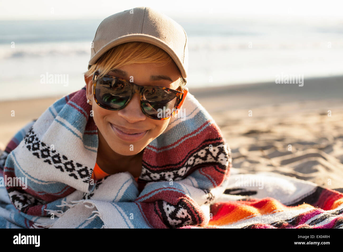 Porträt der jungen Frau am Strand, mit Kappe und Sonnenbrille Stockfoto