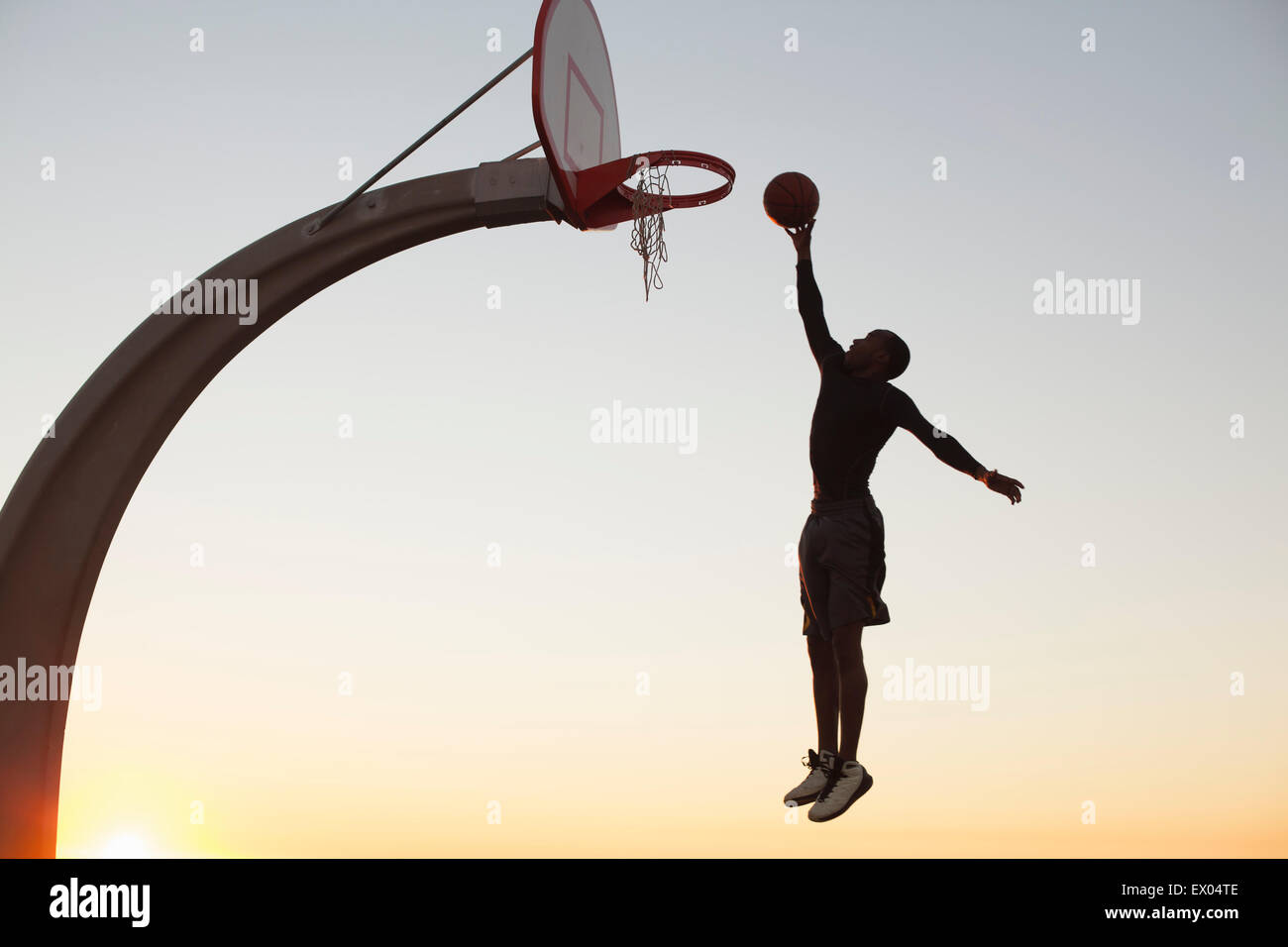 Junger Mann mit Basketball, springen in Richtung Netz, im freien Stockfoto