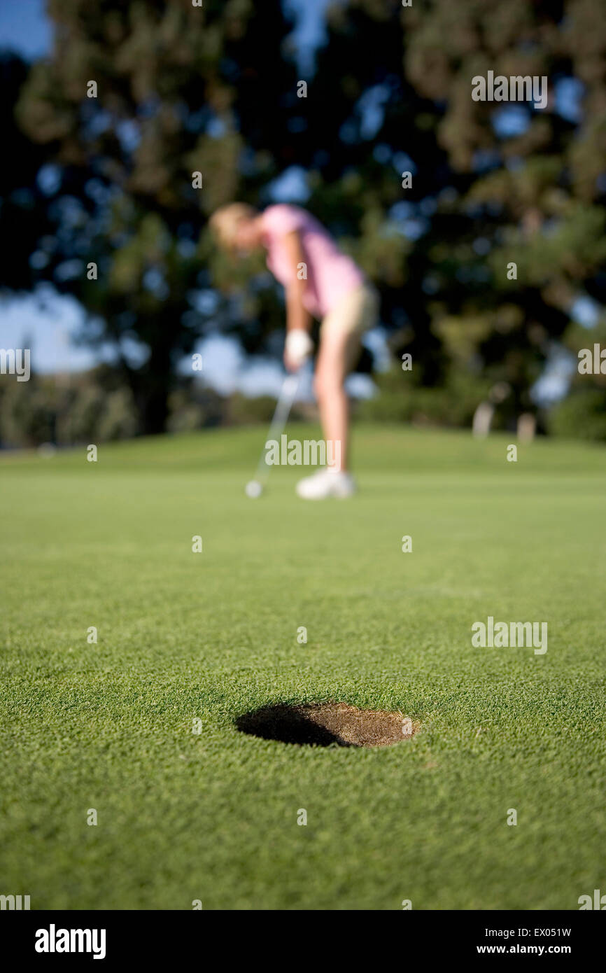 Junge Frau beim Golfen, Fokus auf Vordergrund Stockfoto