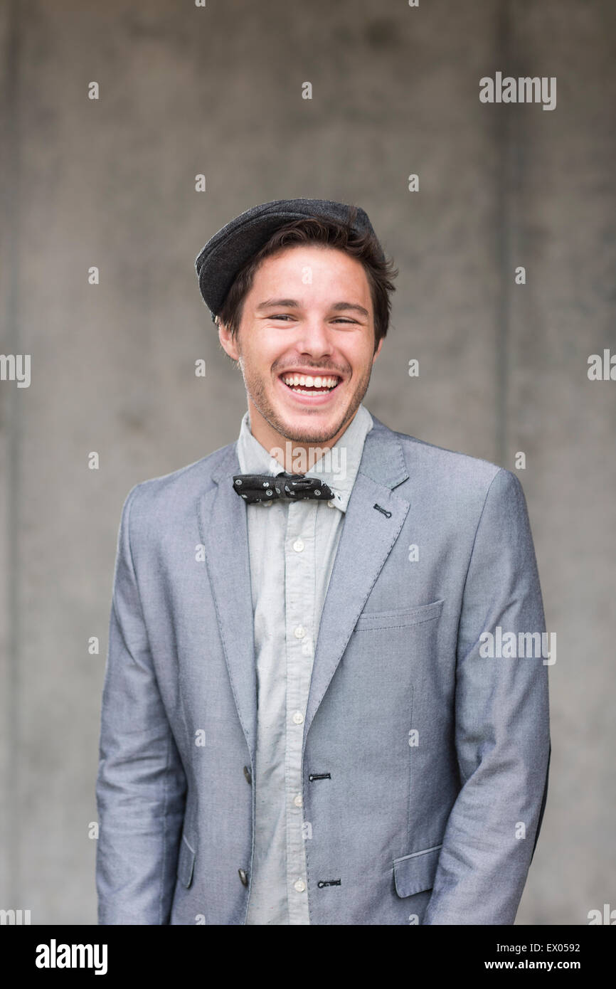 Junger Mann tragen flache Kappe und Fliege, lachen Stockfoto